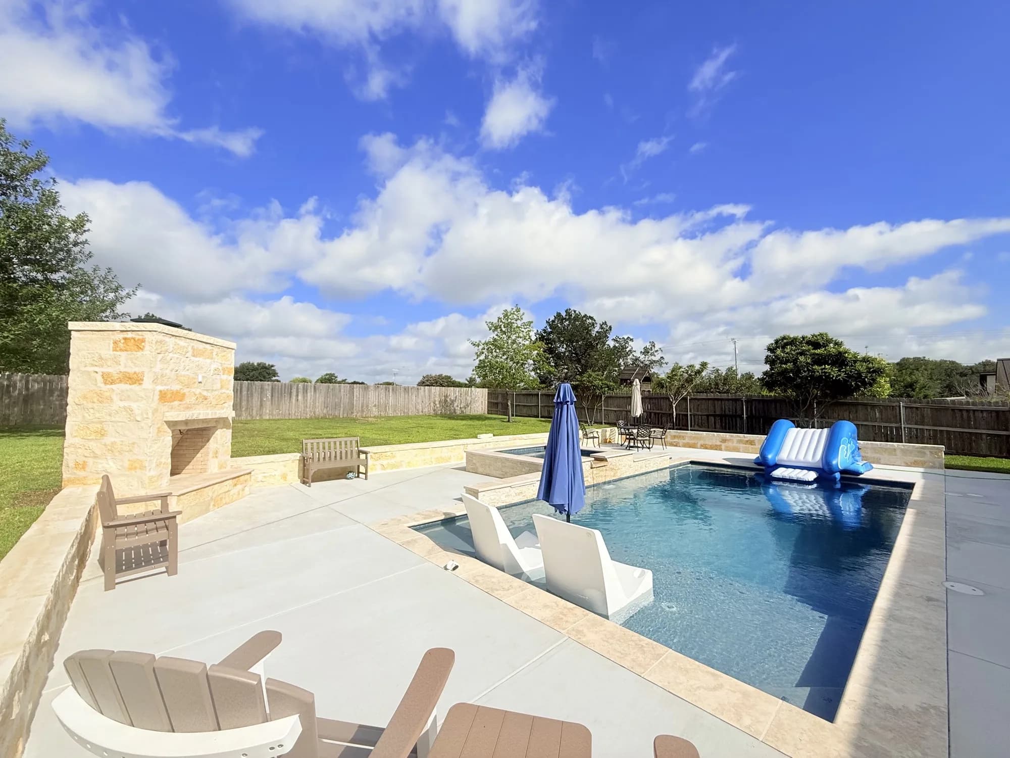 Finished Turner custom gunite pool with raised spa, limestone seating walls, and outdoor fireplace