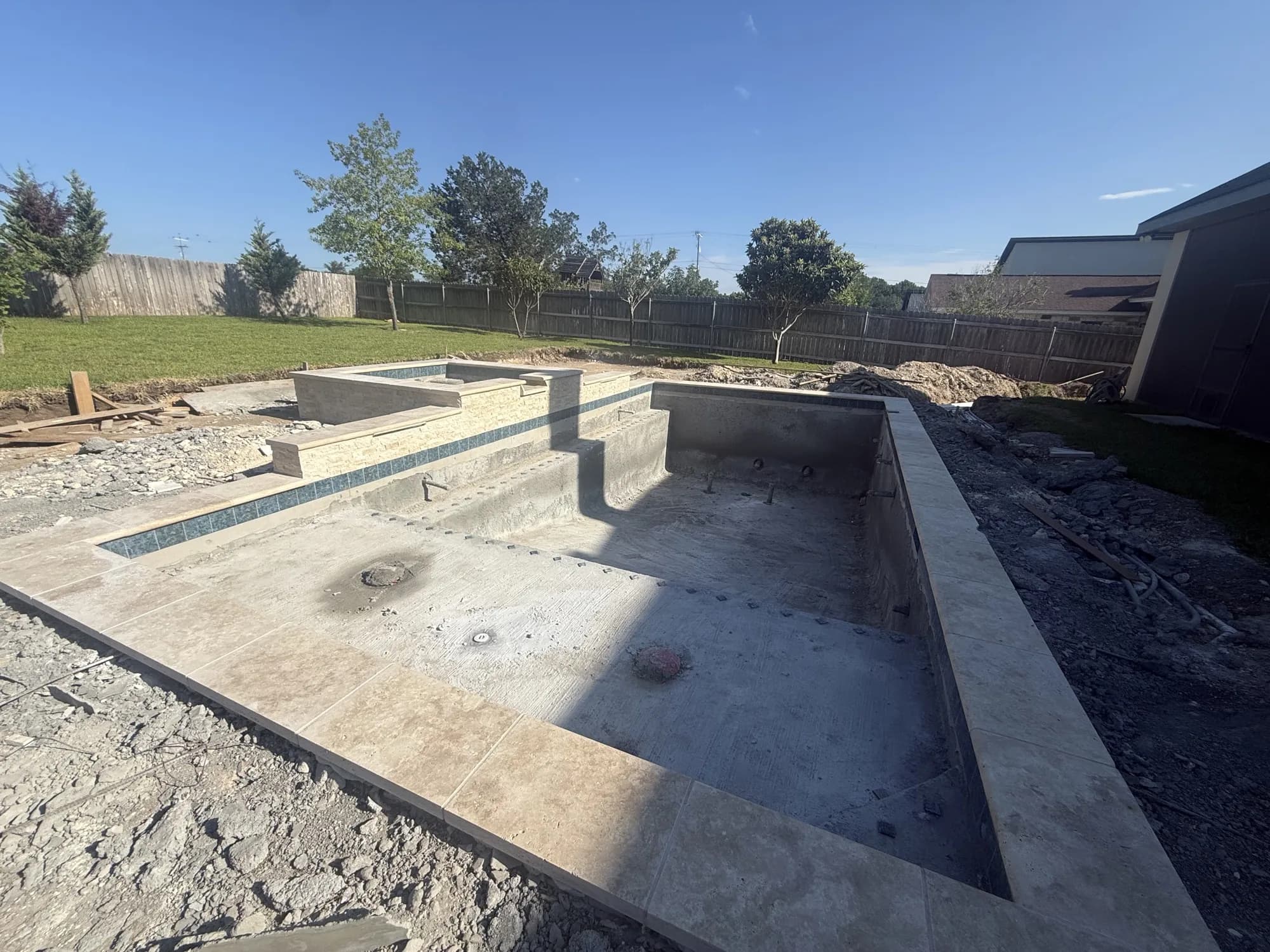 Pre-plaster gunite pool shell showing tile line and travertine coping detail